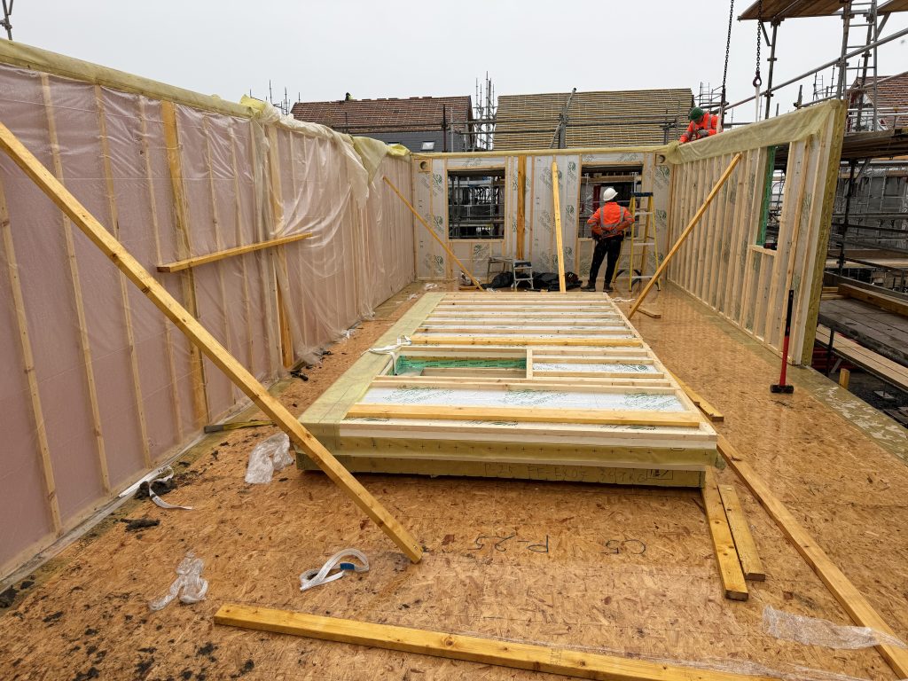 Interior view of a manufactured timber frame structure with wall panels and floor systems in place
